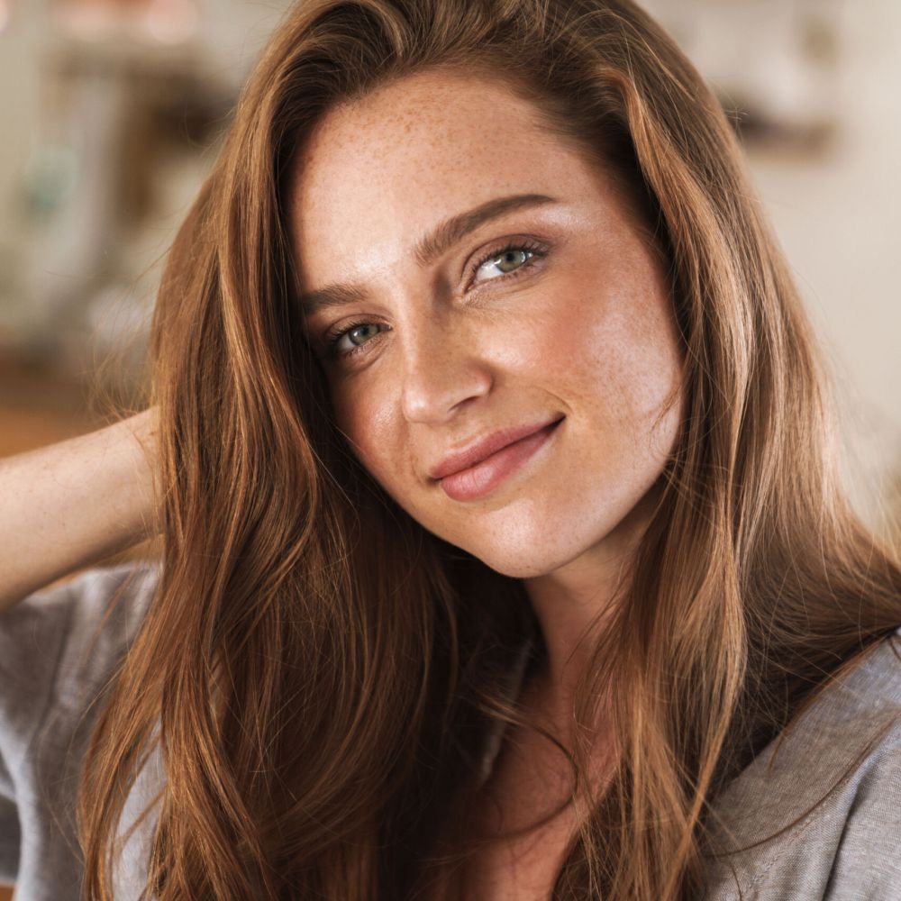 Picture of young cheerful beautiful optimistic happy pleased redhead woman indoors at home.